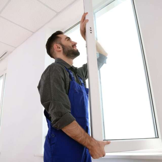 a man in blue overalls looking at a window