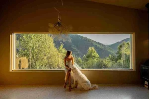 A woman sitting beside a large fixed window with mountain views, using picture windows for natural light