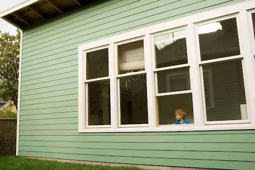 Green residential home with horizontal James Hardie siding installed, showing durable fiber cement siding for long-term exterior protection.