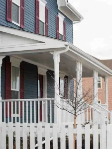 Two-story home with porch featuring James Hardie siding and shutters, showcasing weather-resistant exterior finish.