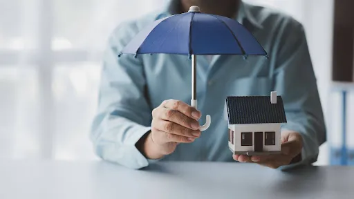 Homeowner holding a model house and umbrella explaining impact windows insurance discount Florida savings.